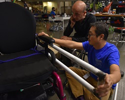 Two teammates measure the device prototype with the power wheelchair Two teammates measure the device prototype with the power wheelchair