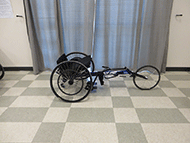Picture of the Top End Eliminator Racing Wheelchair with Open V Cage. This image shows the racing wheelchair into which the subject transferred, and that the structure of the chair differs from a typical manual wheelchair in the height of the seat and a central wheelchair in the front.