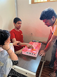 A fourteen year autistic child inserting the shapes on to the device to learn the basic shapes with the help of  device, which is placed on a table along with the trainer