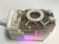 The control module is shown resting on a charging station. Two spring-loaded
charging pins contact the charging nodes at the rear of the device, and a pillar at the front of the charging stand holds the control module in place. A purple light is glowing from the bottom of the charging stand indicating the control module is being charged. When fully charged, the light will turn red.
