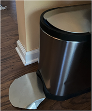 A trash can on the floor with a modified client design. There is a cut on both sides. 